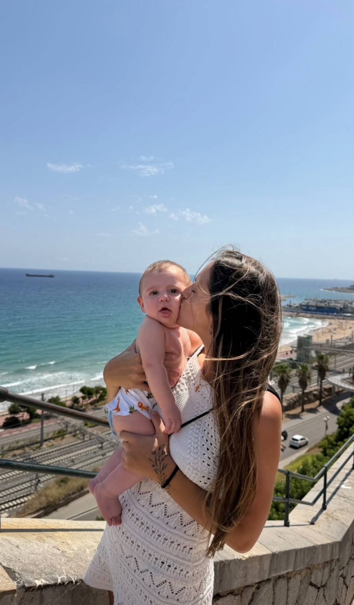 Vero con su bebé en brazos frente al mar en Barcelona
