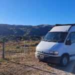 camping para motorhome: casa rodante blanca frente a las sierras al amanecer
