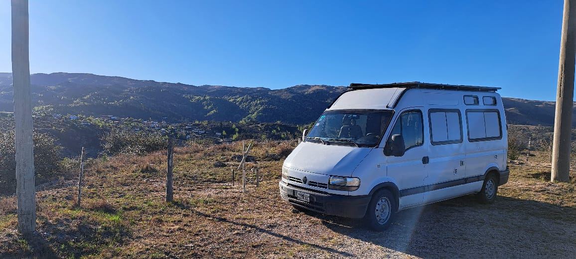 Motorhome blanco estacionado frente a las sierras bajo un cielo azul